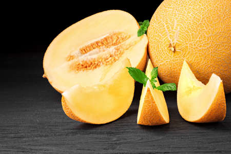 Fresh sweet orange melon on a old black wooden table over black background (selective focus).の写真素材