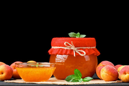 Apricot jam in glass jar on an old black wooden table(selective focus).の写真素材