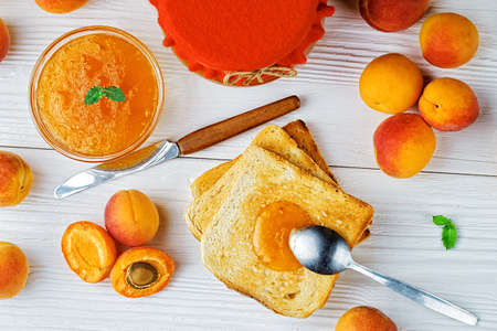 Apricot jam in glass jar on an old white wooden table, top view(selective focus).の写真素材