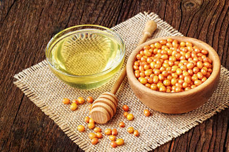 Sea-buckthorn berries and honey on a brown old wooden background (selective focus).Fruit to boost immune system naturally.の写真素材