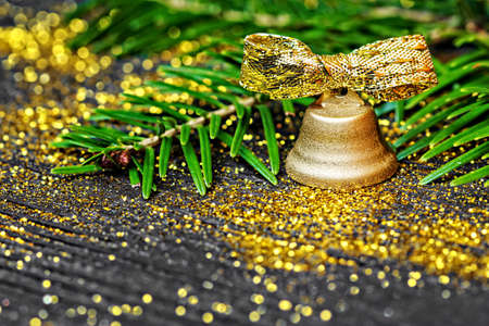Golden bell and pine branches on black wooden background (selective focus).Use it for different holiday greeting cards -  Advent, Christmas or New Yearの写真素材
