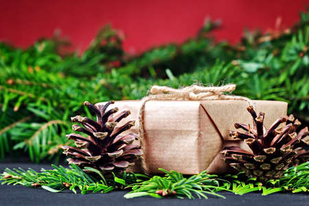 Christmas gift box and pine branches on black wooden table (selective focus).の写真素材
