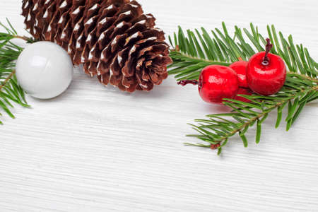 Christmas concept with fir branches, pine cone, and berries on white table (selective focus).の写真素材