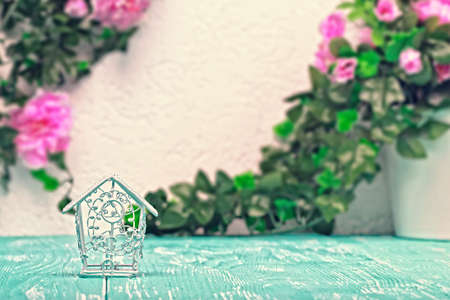 Still life romantic background with decorative bird cage on teal wooden planks and pink flowers on wall in the background (selective focus).の写真素材
