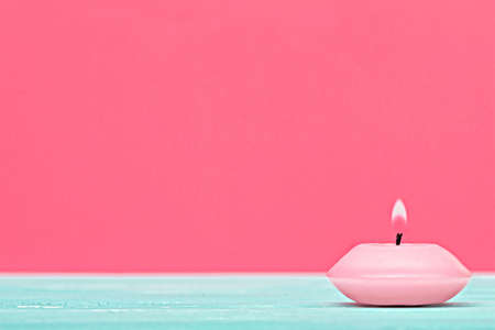 One little candle, isolated on pastel pink background (selective focus).の写真素材