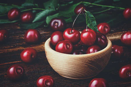 Fresh cherries in bowl on old brown wooden table(selective focus).の写真素材