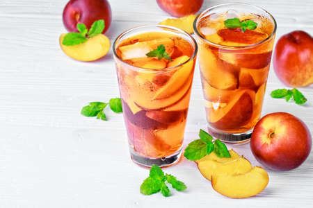Peach ice tea in a glass with mint on a white wooden table(selective focus).の写真素材