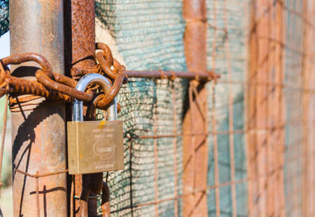 Rusted wire netting in industrial place. Particular of a padlock