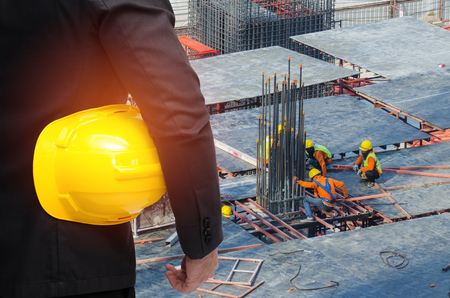 double exposure of businessman hold in hand yellow safety helmet  industrial concept on construction site workers background, color tone effect.の写真素材