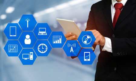 smart businessman in suit using his tablet, business and technology concept with device icon on hexagonal shaped pattern and blurred backgroundの写真素材