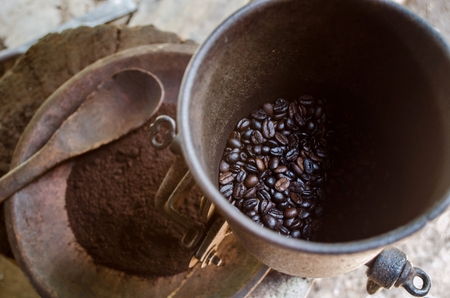 top view of old vintage manual coffee mill or grinder with coffee been and coffee powder with old wooden spoon in background, soft focus, selective focus.の写真素材