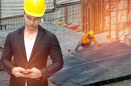 smart construction manager in suite with walkie-talkie or two way radio in hand and yellow safety helmet with construction site worker working at site background, sunlight effectの写真素材