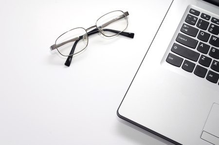Laptop computer with eyeglasses isolate on white background, selective focus, copy spaceの写真素材