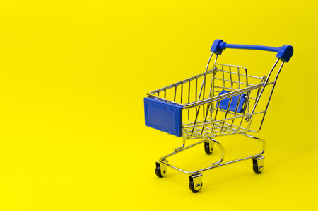 A mini supermarket shopping cart on yellow backgroundの写真素材