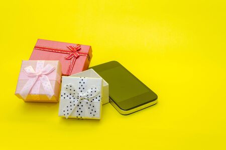 mini colorful gift box and smart phone on yellow background, holiday sale and shopping online concept, selective focus, copy spaceの写真素材