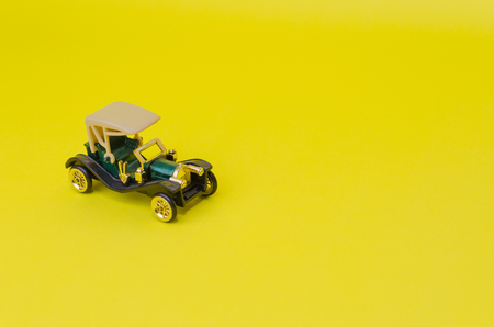 ancient green convertible classic car, old toy car on yellow background, selective focus, copy spaceの写真素材
