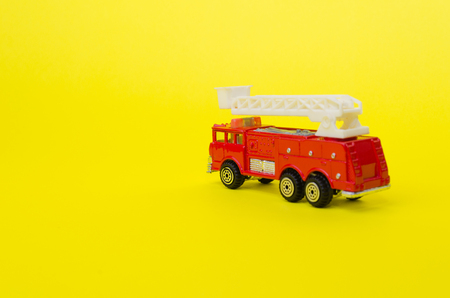 miniature red color fire truck on yellow background, toy car, selective focus, copy spaceの写真素材