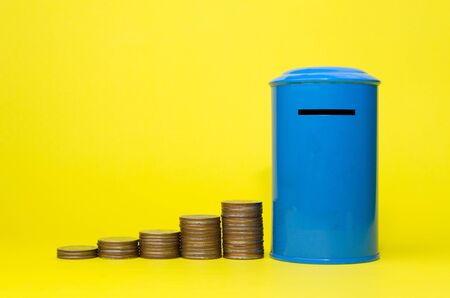 piggy bank or vintage retro blue post box shaped money box with money coin stack growing on yellow background, financial, business, saving money concept, selective focusの写真素材