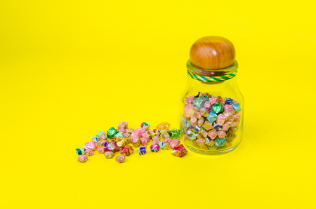 colorful paper star or origami lucky star in a glass bottle for gift on yellow background, selective focus, copy spaceの写真素材