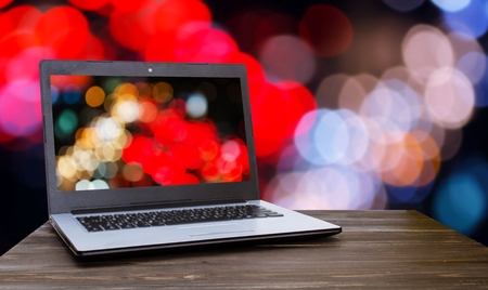 Laptop notebook computer on wooden table with blurred night light bokeh background, selective focus, copy spaceの写真素材