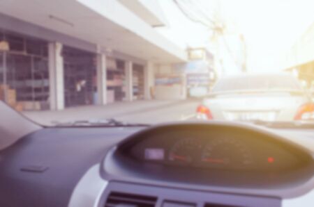 abstract blurred image of view from inside car vintage tone color and sunlight effect, traffic jam on street in the city, transportation and travel conceptの写真素材