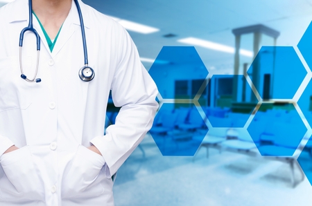 smart doctor with a stethoscope around his neck on blurred image of empty chairs in waiting room at hospital with hexagon shaped pattern design, healthcare medical technology conceptの写真素材