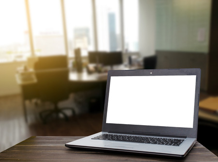 Laptop computer with white blank screen on wooden table with blur business office working space background, selective focus, copy space, business working, online social media, searching data conceptの写真素材