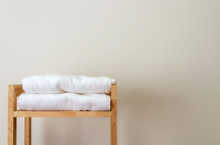 white towels on wooden shelves on white wall in bathroom, selective focus, copy spaceの写真素材