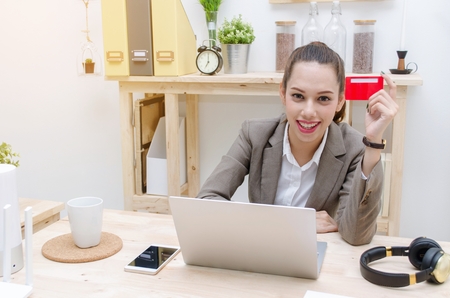 asian young beautiful business woman holding credit card with smartphone and laptop for mobile banking application, sunlight effect, online payment, online shopping, lifestyle technology conceptの写真素材