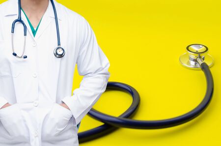 smart doctor with a stethoscope around his neck with stethoscope on yellow background, heart health care and medical technology concept, selective focus, copy spaceの写真素材