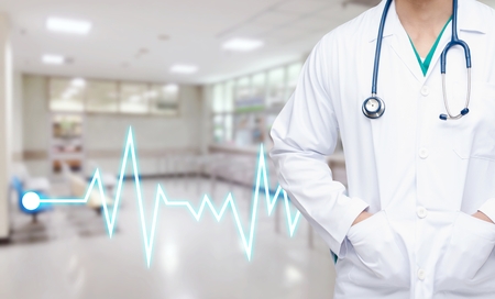 smart doctor with a stethoscope around his neck with heartbeat line and abstract blurred image of empty chairs in waiting room at hospital background heart health care and medical technology conceptの写真素材