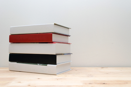stack book on desk, no labels, blank spine with white wall background, education back to school and business concept, copy spaceの写真素材