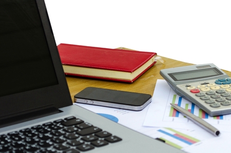 close up business accessories laptop, calculator, datasheet, pen, notebook and smartphone on desk isolated on white background, financial report, saving and economy business concept, selective focusの写真素材