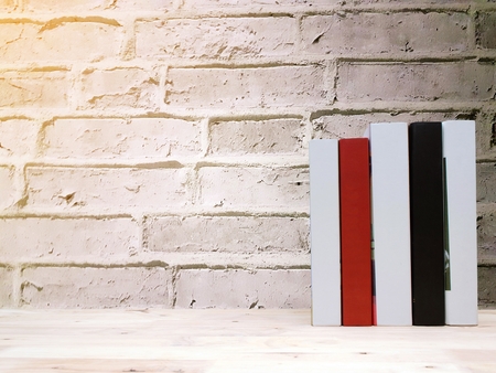 stack book on desk, no labels, blank spine with brick wall background, selective focus, copy space, sunlight effect, education back to school and business concept, color tone effectの写真素材