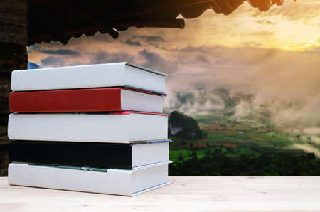stack book on desk, no labels, blank spine with blurred view of beautiful nature landscape with sunlight in summer at the morning background, education back to school, landscape nature conceptの写真素材