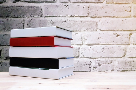 Stack book on desk without labels, blank spine with brick wall background.の写真素材