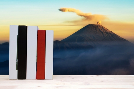 stack book on desk, no labels, blank spine with blurred view of active volcano of Bromo National Park, Java, Indonesia at morning, education back to school, landscape nature, copy spaceの写真素材