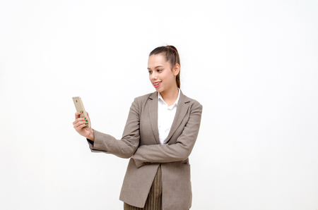 Portrait of asian young beautiful smiling business woman standing and holding smartphone isolated on white backgroundの写真素材