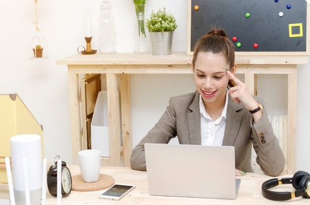 asian young business woman beautiful smile working on laptop computer on wooden desk, soft focus, sunlight effect, social network media technology, business lifestyle and working woman conceptの写真素材