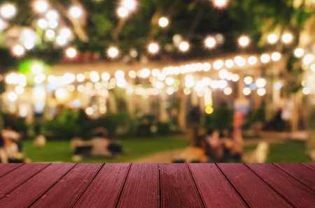 empty red wooden floor or wooden terrace with abstract night light bokeh of night festival in garden, light blurred background, copy space, vintage color toneの写真素材