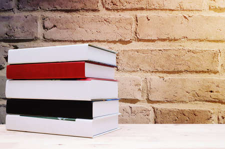 stack book on desk, no labels, blank spine with brick wall background, selective focus, copy space, sunlight effect, education back to school and business concept, color tone effectの写真素材