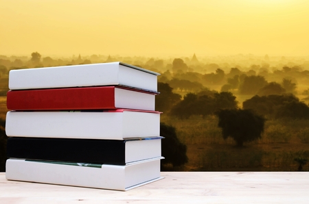 stack book on desk, no labels, blank spine with blurred view of beautiful sunrise of ancient pagoda and temple in Bagan, Myanmar, education back to school, landscape nature, history conceptの写真素材