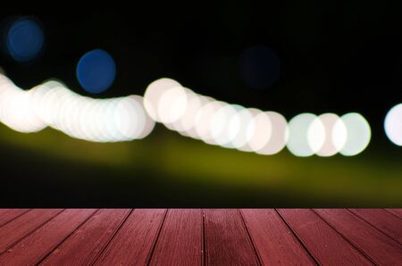 empty red wooden floor or wooden terrace with abstract night light bokeh of night festival in garden, light blurred background, copy space, vintage color toneの写真素材