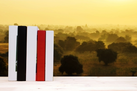 stack book on desk, no labels, blank spine with blurred view of beautiful sunrise of ancient pagoda and temple in Bagan, Myanmar, education back to school, landscape nature, history conceptの写真素材