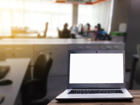 Laptop computer with white blank screen for advertising on wooden desk with blur business office working space background, copy space, business working, online social media, searching data conceptの写真素材