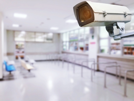 CCTV, security camera system operating in hospital with blurred image of empty chairs in waiting zone for pay money and receive medicine at cashier pharmacy counter at hospital or clinicの写真素材