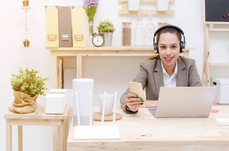 asian young business customer service woman smiling in headset working with laptop, business woman listening music with headphones in office, business technology lifestyle concept, soft focusの写真素材