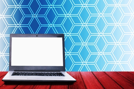 white blank screen laptop computer on wooden desk for presentation with abstract hexagon pattern design in blue and white color tone background, business technology, workspace concept, copy spaceの写真素材