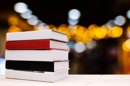 stack book on desk, no labels, blank spine with blurred image of abstract night light bokeh on dark background, education back to school concept, copy spaceの写真素材