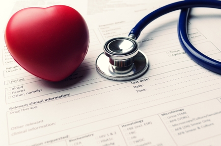 stethoscope with red heart and patient information form on desk, healthcare technology, medical report record and history patient concept, selective focus, vintage color toneの写真素材
